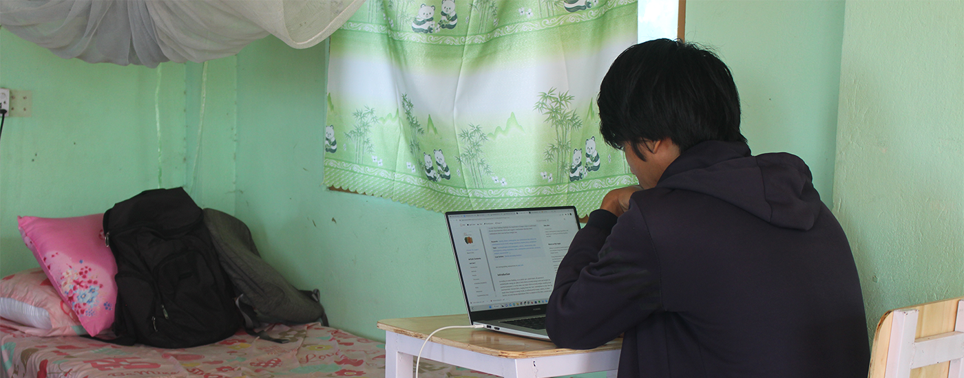 Student studying at his laptop in his bedroom